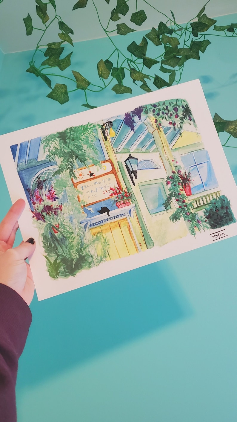 May include: A watercolor painting of a building with a yellow door and a sign that reads "Today's Special is..." in Japanese. The building is surrounded by green plants and flowers. A black cat is sitting on a windowsill.