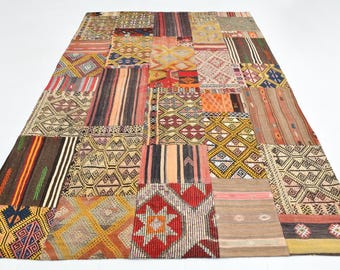 May include: A large, rectangular patchwork rug with a variety of geometric and striped patterns in shades of brown, red, orange, yellow, and cream. The rug is made up of numerous individual pieces sewn together.