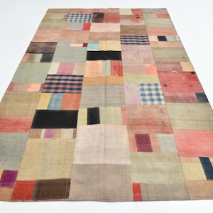 Può includere: Un tappeto rettangolare con un design patchwork composto da vari segmenti di tessuto in tonalità tenui di rosso, blu, giallo, grigio e beige. Il tappeto include diverse sezioni con motivi a quadri blu e bianchi e blocchi di colore solido.