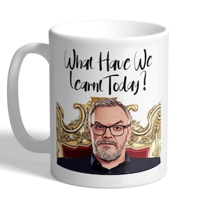 May include: White ceramic mug featuring a black and white image of a man with a beard and glasses seated on a gold throne. The text "What Have We Learnt Today?" is printed in black on the mug.