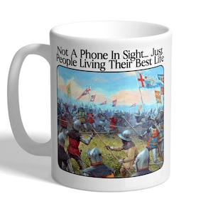 May include: White ceramic mug with a handle. The mug features a medieval battle scene illustration with soldiers in armour and flags. The text on the mug reads "Not A Phone In Sight... Just People Living Their Best Life."