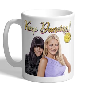 May include: White ceramic mug with a gold and red "Keep Dancing!" text, featuring a photo of two women with a gold disco ball.