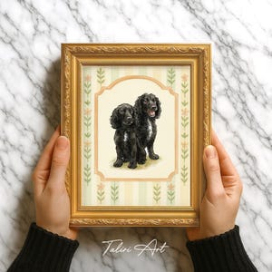 Może przedstawiać: Oprawiony obraz akwarelowy przedstawiający dwa czarne psy. Grafika jest umieszczona w złotej ramie z ozdobną bordiurą z kwiatów i liści. Obraz jest podpisany "Taliri Art" w prawym dolnym rogu.