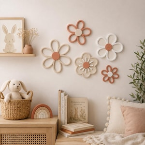 Op de afbeelding: Een set van vijf aan de muur gemonteerde bloemdecoraties in terracotta, wit en beige. De set bevat drie bloemvormige contouren met massieve ronde centra en twee massieve bloemen met gedetailleerde texturen op de bloemblaadjes en in het midden.