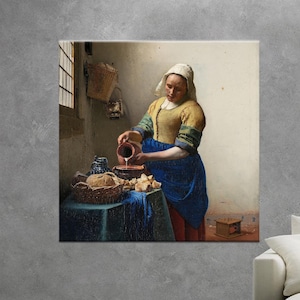 Puede incluir: Impresión en lienzo de una pintura clásica que representa a una mujer con una blusa amarilla y una falda azul vertiendo líquido de una jarra. Una mesa con pan y una cesta está en primer plano. La pintura tiene una paleta de colores cálidos.