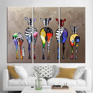 May include: A multi-panel canvas print featuring a group of colorful zebras with black and white stripes. The zebras are depicted from the rear, with their tails and legs visible. The background is a muted brown color.
