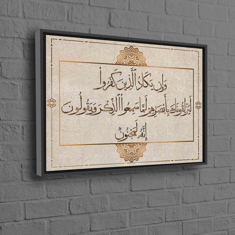 May include: A beige canvas print with a gold frame features an Islamic calligraphy quote in Arabic script. The quote is surrounded by a decorative gold mandala design.