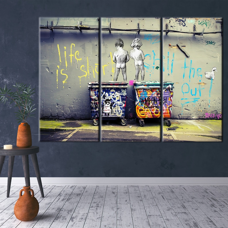 May include: A graffiti-covered wall with the words "Life is short, still the one" painted in yellow. Two figures stand in front of the wall, with their backs to the viewer, and two large, colorful trash cans are in front of them.