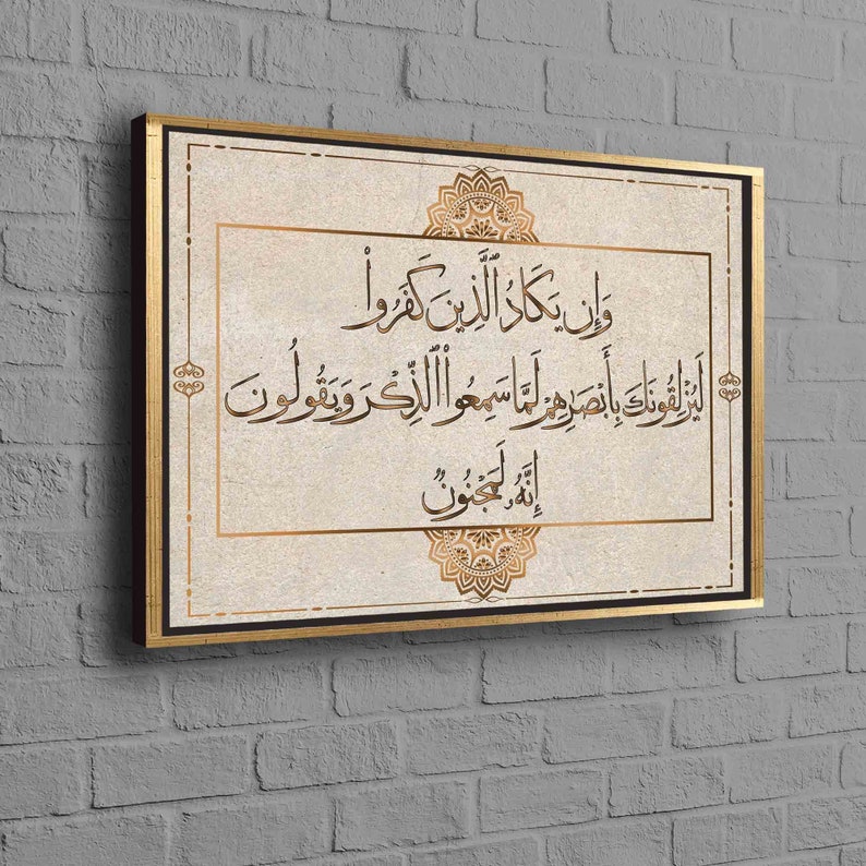 May include: A canvas print with a gold frame featuring an Islamic quote in Arabic script. The quote is surrounded by a decorative mandala design. The background is a light beige color.