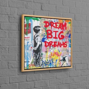 May include: A colourful abstract painting featuring a young boy standing in front of a wall with the words "DREAM BIG DREAMS" in red paint.