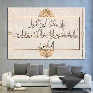 May include: A canvas print with a gold frame and intricate gold designs. The print features Arabic calligraphy in a beige color on a white background. The text reads "Wa lakal akhira wa laka al-awla" which translates to "And for you is the Hereafter, and for you is the first."