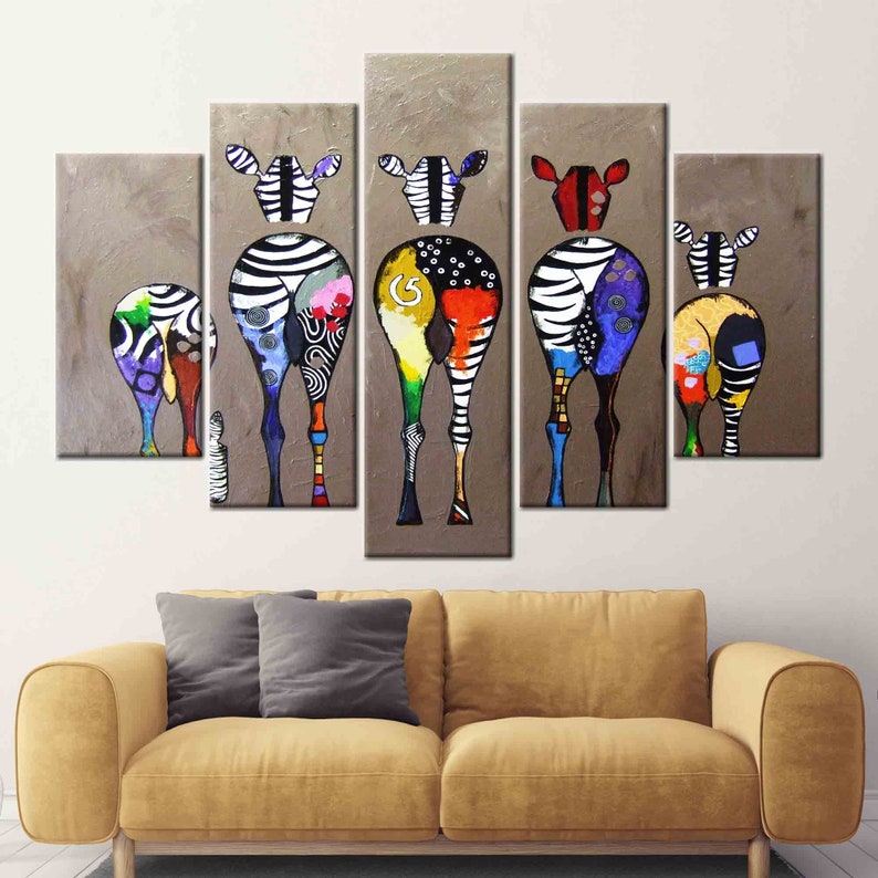 May include: A multi-panel canvas painting featuring five colorful zebras with black and white stripes. The zebras are painted in a whimsical style with bright colors and patterns. The background is a light brown color.
