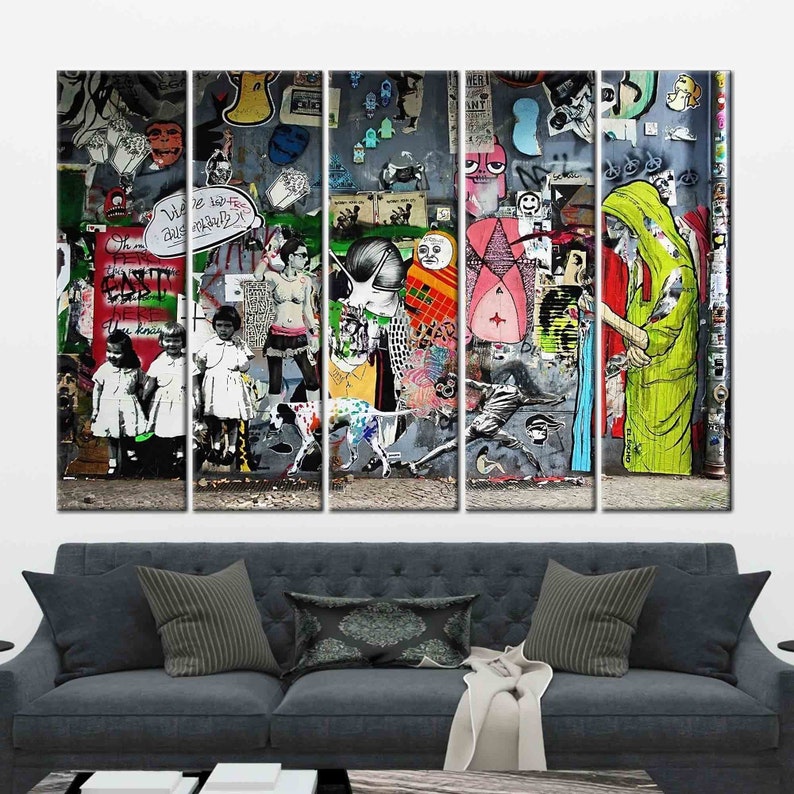 May include: A multi-panel wall art print featuring a colorful and abstract graffiti mural with various figures, symbols, and text. The mural is painted on a gray wall and includes a variety of colors, including red, blue, green, yellow, and black.