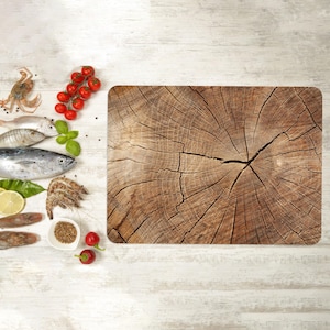 May include: A wooden cutting board with a natural wood grain pattern. The board is surrounded by various ingredients, including fresh fish, shrimp, tomatoes, and herbs.