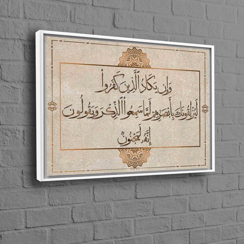 May include: A beige canvas print with a white frame features an Islamic calligraphy quote in gold lettering. The quote is surrounded by decorative gold floral designs.