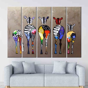 May include: A set of five colorful abstract zebra paintings on canvas. Each zebra is painted in a different color scheme with black and white stripes. The zebras are all facing the same direction and are standing in a row. The background is a light brown color.