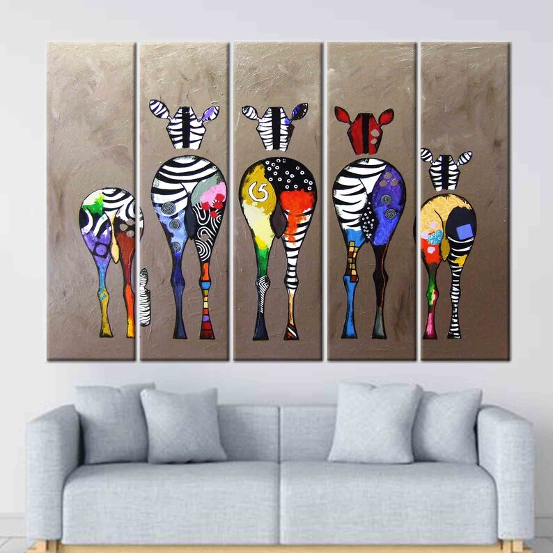 May include: A set of five colorful abstract zebra paintings on canvas. Each zebra is painted in a different color scheme with black and white stripes. The zebras are all facing the same direction and are standing in a row. The background is a light brown color.