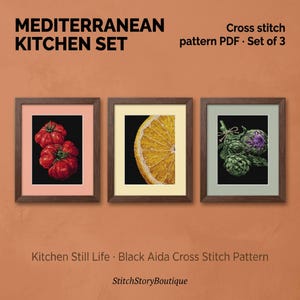Pode incluir: Um conjunto de três padrões de ponto cruz emoldurados intitulado Mediterranean Kitchen Set. As imagens apresentam um tomate vermelho, uma fatia de laranja amarela e alcachofras verdes em fundos pretos, em molduras de madeira com passe-partout.