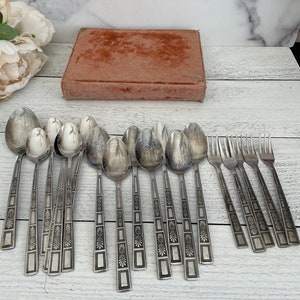 May include: A set of 18 silver-toned flatware with ornate designs on the handles. The flatware includes spoons and forks.