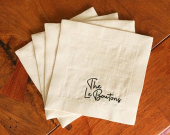 May include: Set of five off-white linen napkins with black embroidered text "The Le Boutons".