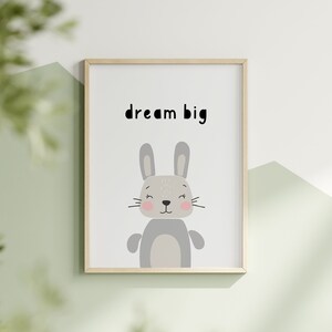 K&ouml;nnte beinhalten: Gerahmter Druck mit einem Cartoon-Hasen und dem Text "dream big". Der Hase ist grau mit rosa Wangen und einem hellgrauen K&ouml;rper. Der Rahmen ist aus hellem Holz, der Hintergrund ist wei&szlig; und gr&uuml;n.