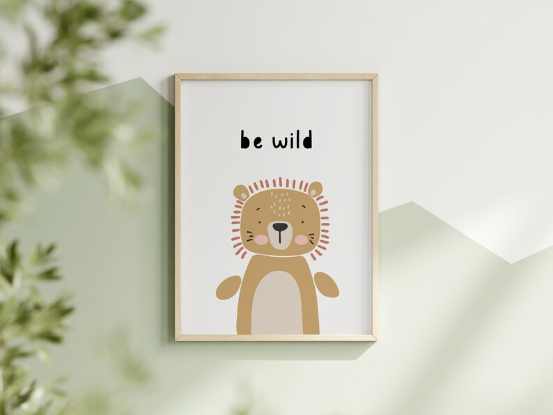 K&ouml;nnte beinhalten: Ein gerahmter Kunstdruck mit einer Cartoon-L&ouml;wen-Illustration in Braun-, Beige- und Pfirsicht&ouml;nen. Der Text "be wild" ist &uuml;ber dem L&ouml;wen aufgedruckt. Das Kunstwerk ist vor einem wei&szlig;en Hintergrund und in einem hellen Holzrahmen gerahmt.