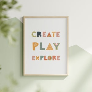 May include: A framed print with the words "CREATE PLAY EXPLORE" in colorful, patterned letters on a white background.
