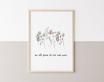May include: A framed print with a watercolor illustration of a row of pink and green flowers. The text "we all grow at our own pace" is printed below the flowers.