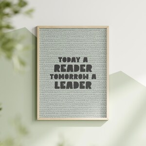 Op de afbeelding: Een ingelijst print met een lichtblauwe achtergrond en een wit patroon. De print bevat de tekst "Today a Reader Tomorrow a Leader" in zwart.