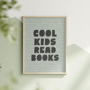 Puede incluir: Una impresión enmarcada con un fondo azul claro y un patrón blanco. La impresión dice "Cool Kids Read Books" en letras negras.