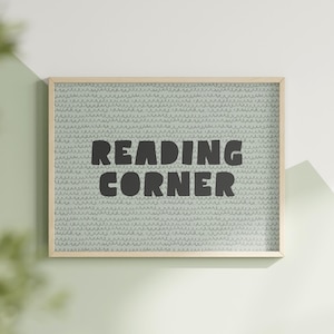 Może przedstawiać: Wydruk w ramie z jasnoniebieskim tłem i czarno-białym wzorem. Wydruk zawiera napis "Reading Corner" czarnymi pogrubionymi literami.