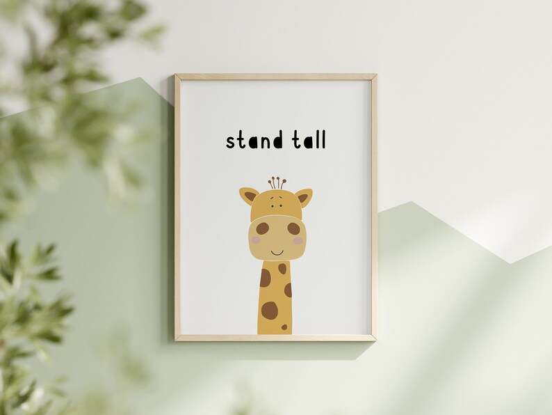 K&ouml;nnte beinhalten: Gerahmter Druck mit einer Cartoon-Giraffen-Illustration. Die Giraffe ist beige mit braunen Flecken und einem hellbraunen Kopf. Die Worte "stand tall" stehen in Schwarz &uuml;ber der Giraffe. Der Rahmen ist hellbraun.
