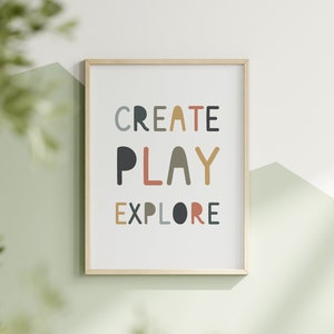 May include: A framed print with the words "CREATE PLAY EXPLORE" in colorful, stylized lettering on a white background.