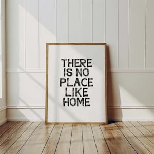 May include: A framed print with the text "THERE IS NO PLACE LIKE HOME" in black lettering on a white background.
