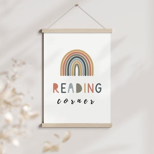 Puede incluir: Una impresión en lienzo blanco con un arcoíris colorido y el texto "READING corner" en una fuente divertida.