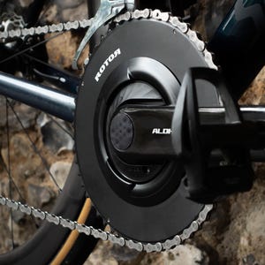 Peut inclure: Gros plan sur un pédalier de vélo noir avec une chaîne argentée. Le pédalier porte l'inscription "ROTOR" et le mot "ALDHU" est visible sur le bras.