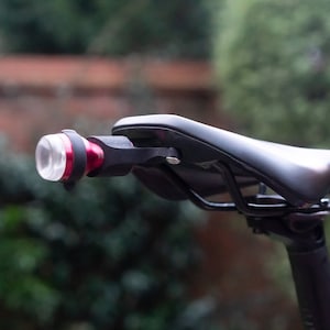 Peut inclure: Une selle de vélo noire avec un feu de vélo rouge et noir fixé à l'arrière.