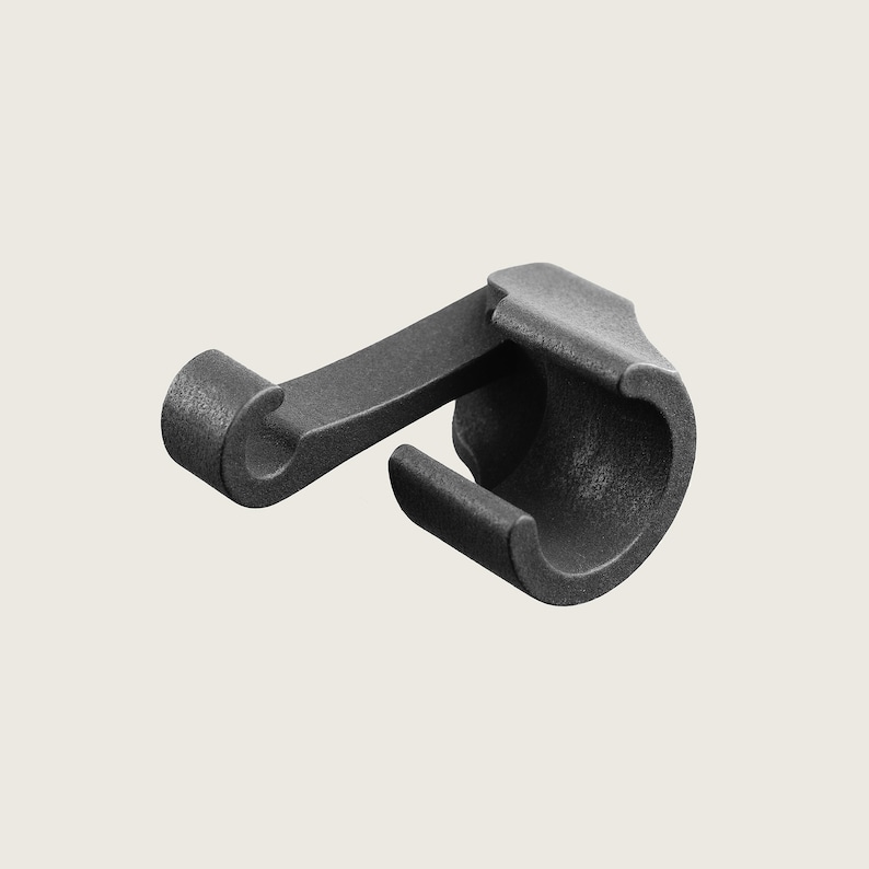 May include: Black plastic hook with a curved design. The hook is designed to be attached to a surface and has a small loop at the end for hanging items.