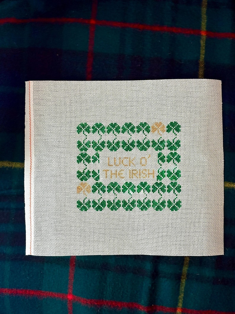 May include: White canvas with a green and gold cross-stitch design. The design features a border of shamrocks and the text "Like the Irish".