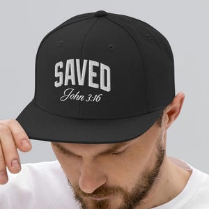 May include: A black baseball cap with a white embroidered design that says "SAVED John 3:16".