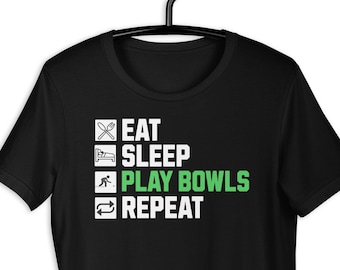 May include: Black t-shirt with a white graphic that reads "Eat, Sleep, Play Bowls, Repeat". The graphic is in a checklist format with a green checkmark next to "Play Bowls".