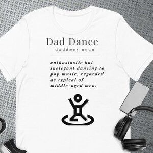 Könnte beinhalten: Weißes T-Shirt mit einem schwarzen Grafikdesign, das "Dad Dance" als "begeisterter, aber unelegant Tanz zu Popmusik, der als typisch für Männer mittleren Alters gilt" definiert.