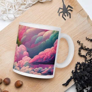 Puede incluir: Taza de cerámica blanca con un diseño abstracto colorido de nubes rosas, azules y verdes. La taza tiene un asa blanca.