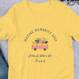 Op de afbeelding: Geel T-shirt met een roze vintage busje met bloemen erop. De tekst op het shirt luidt "Making Memories 2022" en "Home is where we park it."