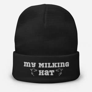 Puede incluir: Gorro negro con el texto "my milking hat" en blanco con dos siluetas de vacas a cada lado del texto.