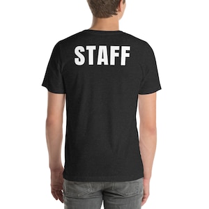 Könnte beinhalten: Ein dunkelgraues T-Shirt mit dem Wort "STAFF" in Weiß auf dem Rücken.