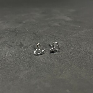 May include: A pair of silver heart-shaped earrings.