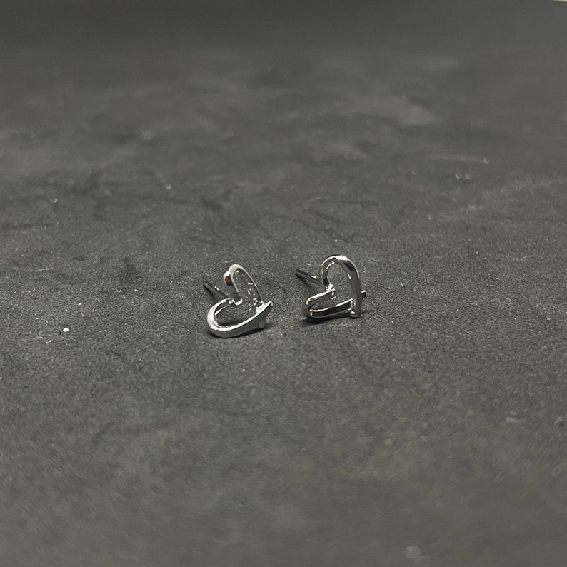May include: A pair of silver heart-shaped earrings.