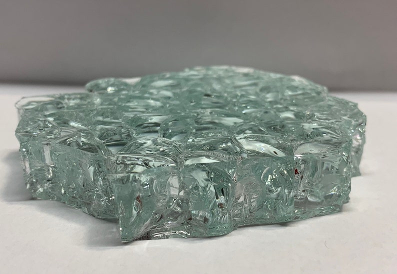 May include: A close-up of a light green, textured glass tile. The tile is made of many small, irregular pieces of glass that have been fused together.