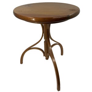 May include: A small, round wooden side table with a dark brown finish. The tabletop is supported by three curved legs. The table is likely made of hardwood and has a classic, vintage design.